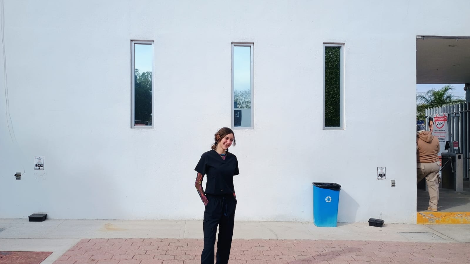 Daniela del Río con uniforme clínico de fisioterapia frente a su universidad